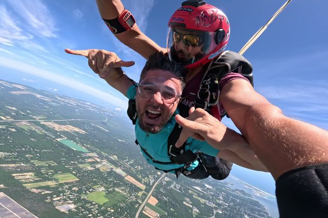 man free falling mid air attached to skydiving instructor