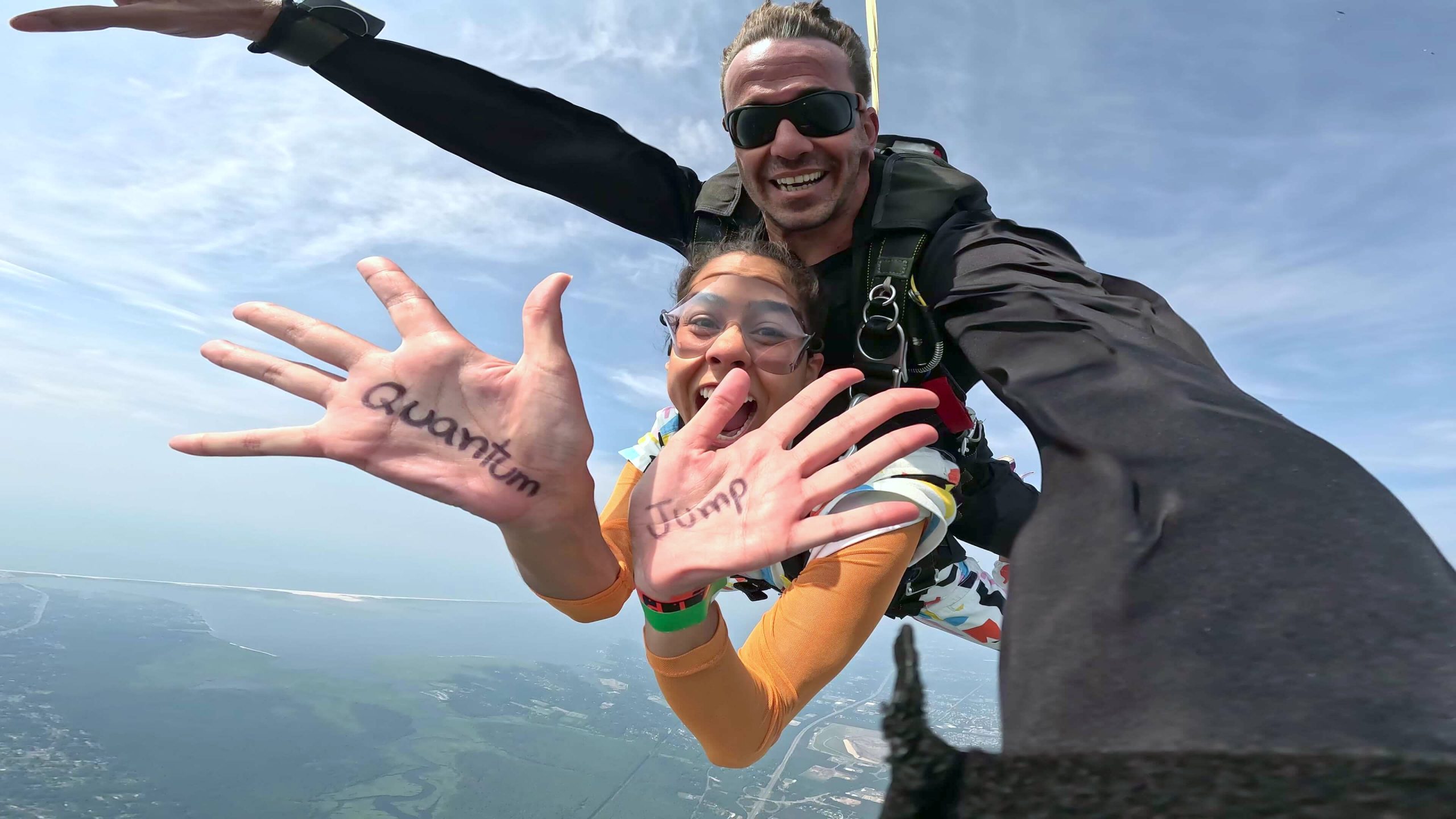Girl jumping out of a plane with th ewords "quantum jump" written on her hands.